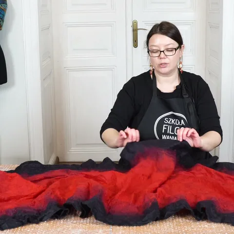 Module 2: Justyna stretching the rippled black edge of the felted red Flamenco shawl