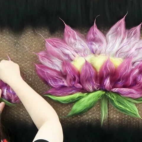 Module 3: a lotus flower of shaded pink wool and silk petals with green leaves, laid out on black silk